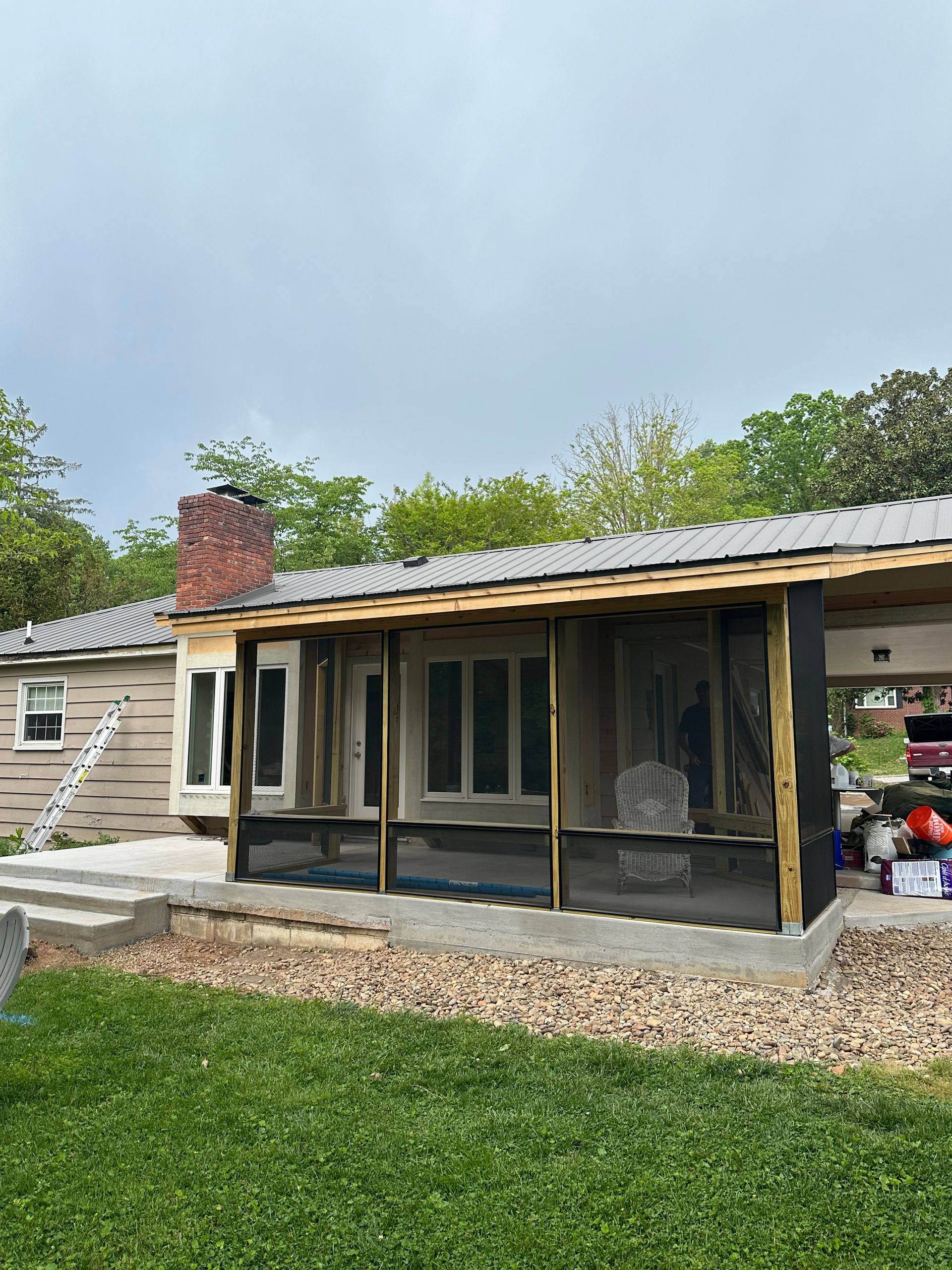 A house with a screened in porch and a chimney.