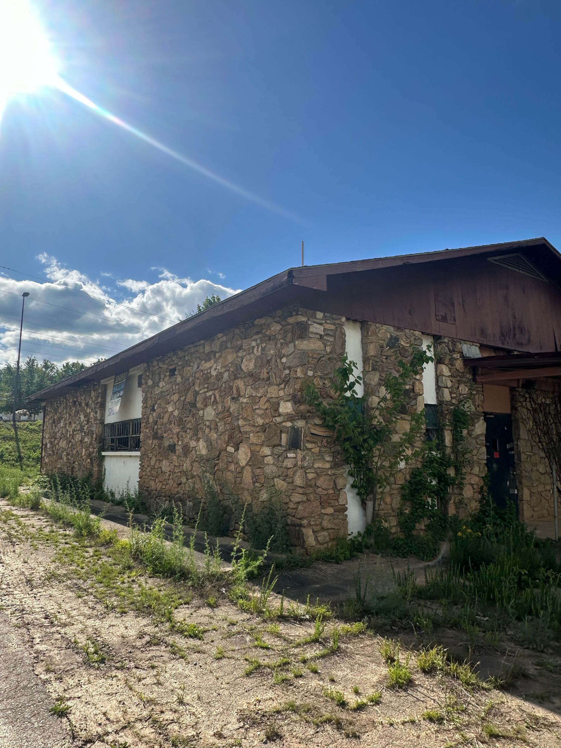 A stone house with a wooden roof and a blue sky in the background.