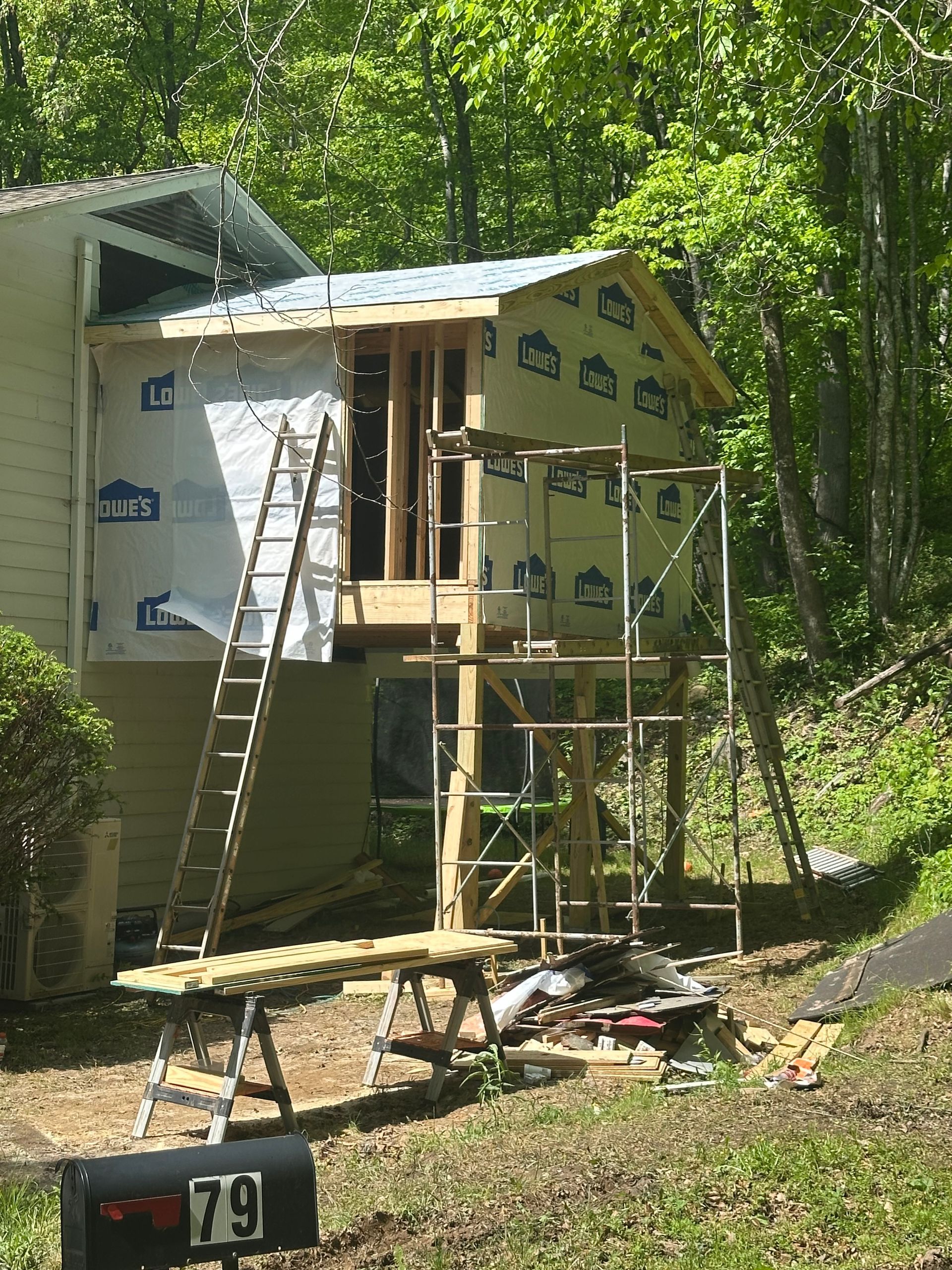 A house is being remodeled with scaffolding and a mailbox with the number 79 on it