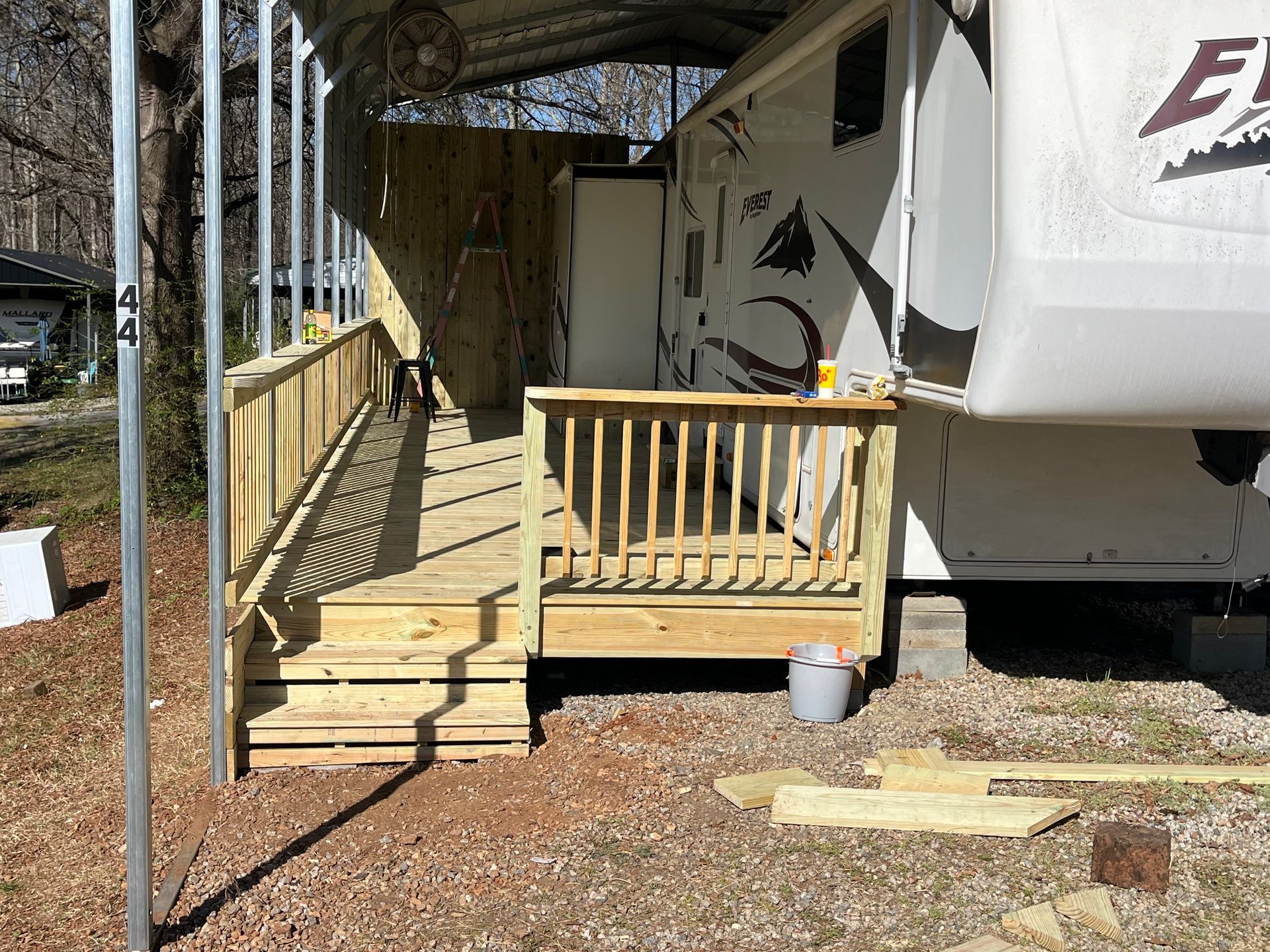 A rv with a wooden deck and stairs attached to it.