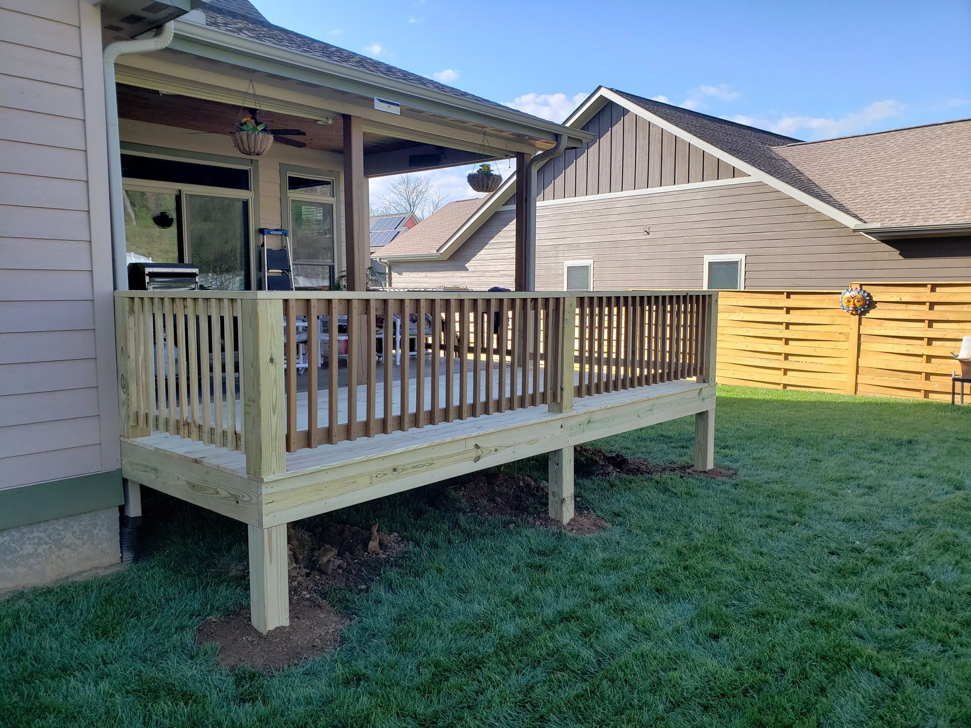 A wooden deck is in the backyard of a house.