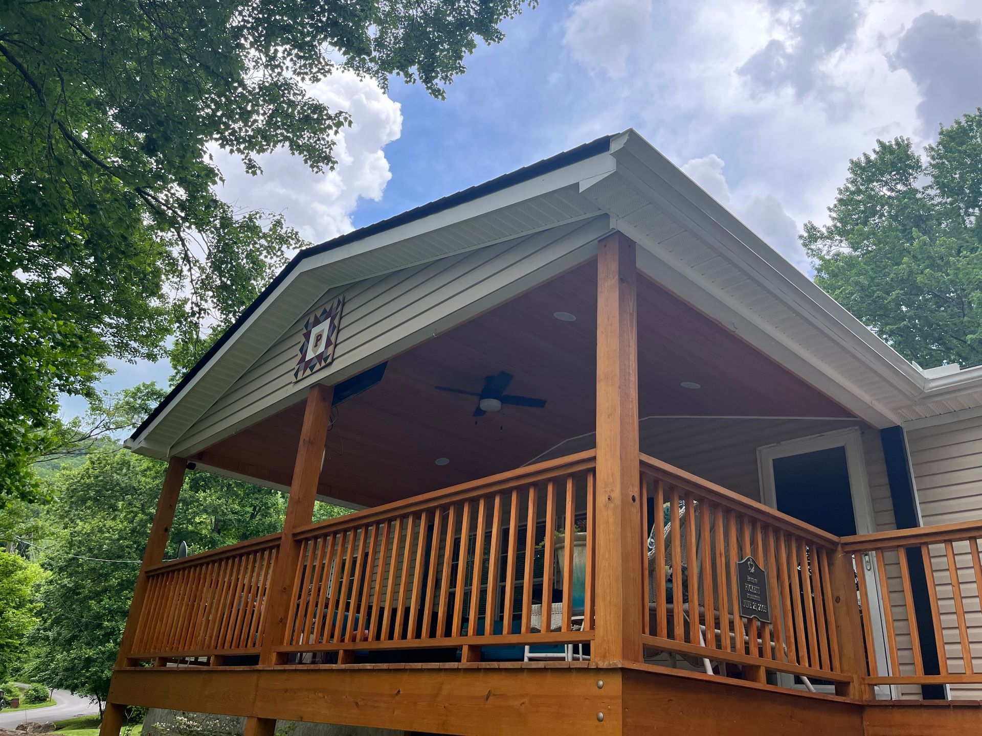 A large wooden deck with a ceiling fan on top of it.
