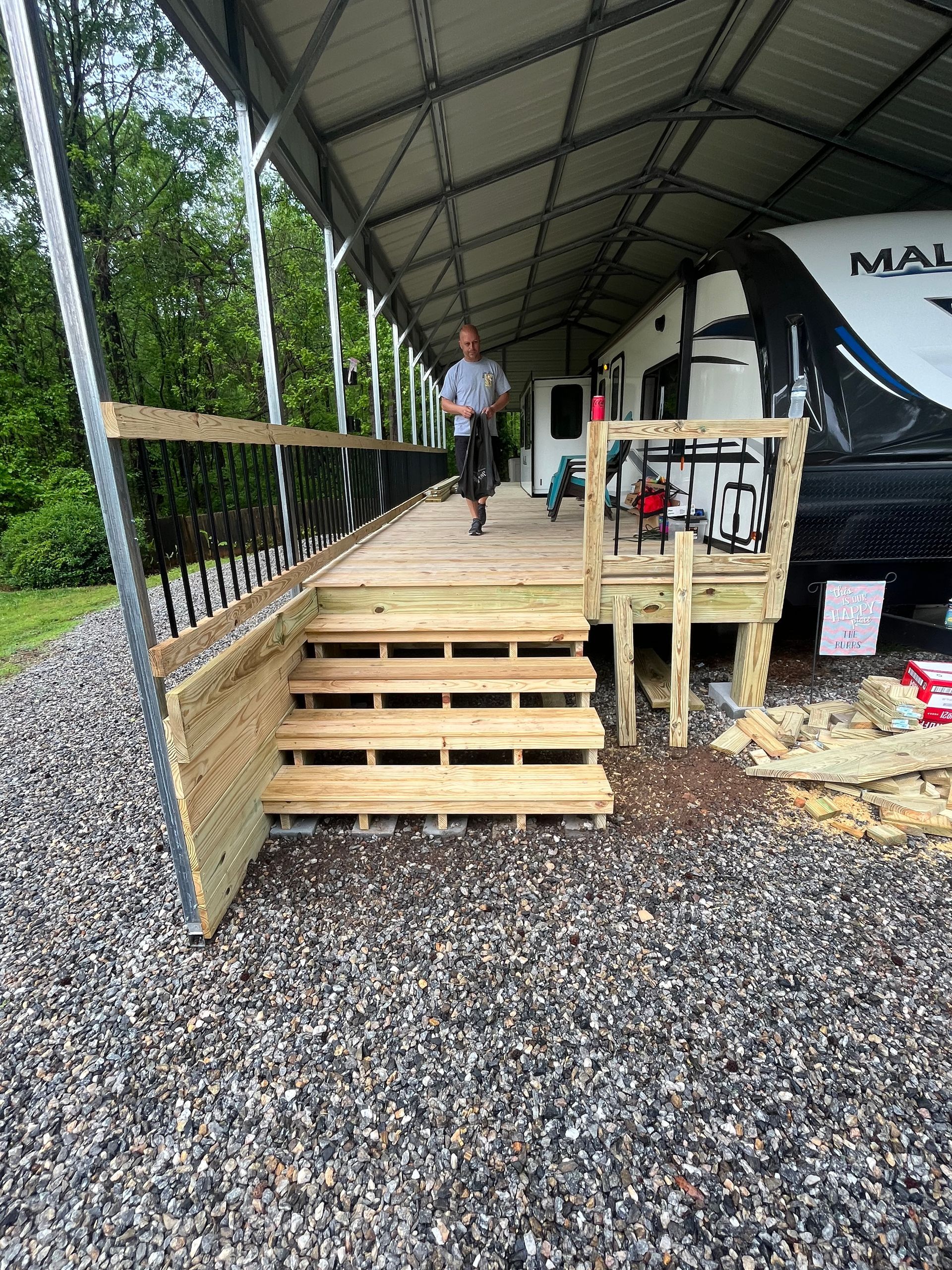A man is standing on a wooden deck next to a rv.
