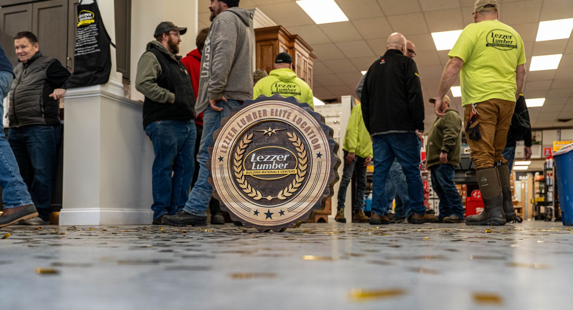 People standing indoors around a large round wooden disc at a workshop or market space.