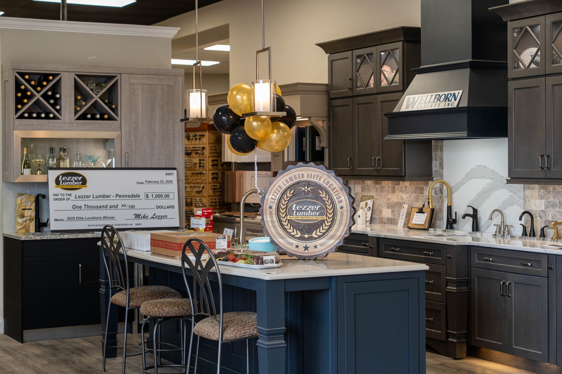 Modern kitchen showroom with dark cabinetry, white cabinets, and a decorated island display