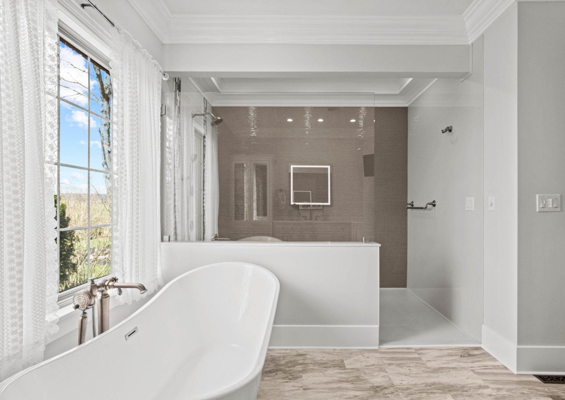 Bright modern bathroom with a freestanding tub, glass shower, and gray tile accents.
