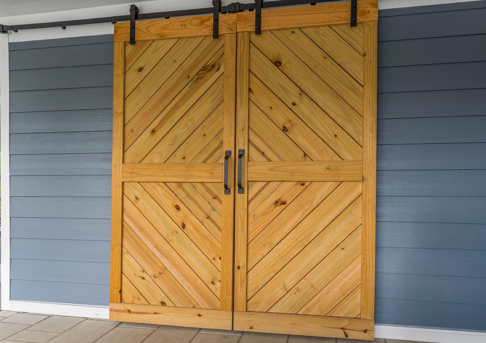 Wooden double barn doors with diagonal planks on a blue-gray wall