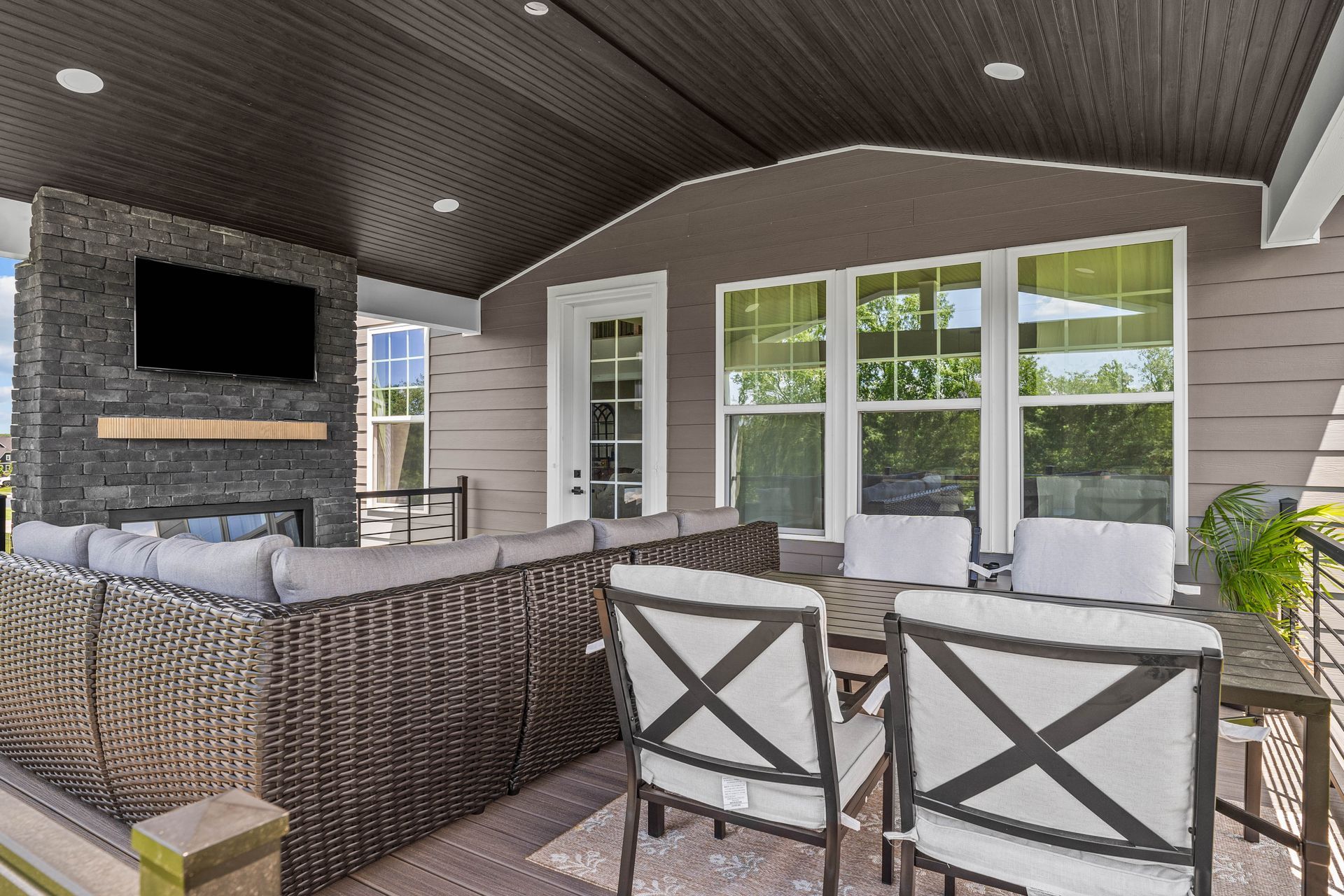 Covered patio with wicker seating, stone fireplace, and sliding glass doors.