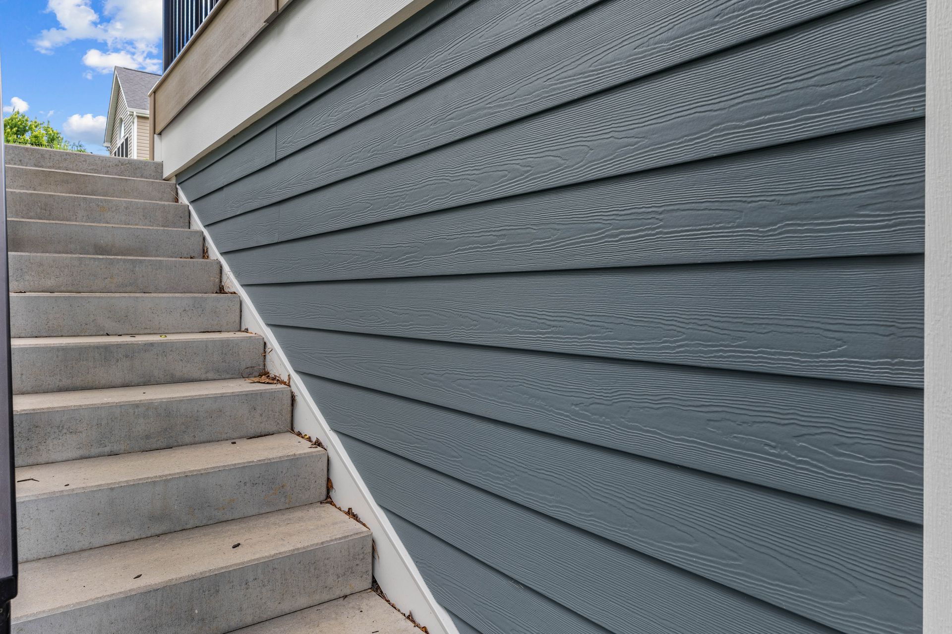 Concrete stairway beside a gray-blue siding wall outdoors