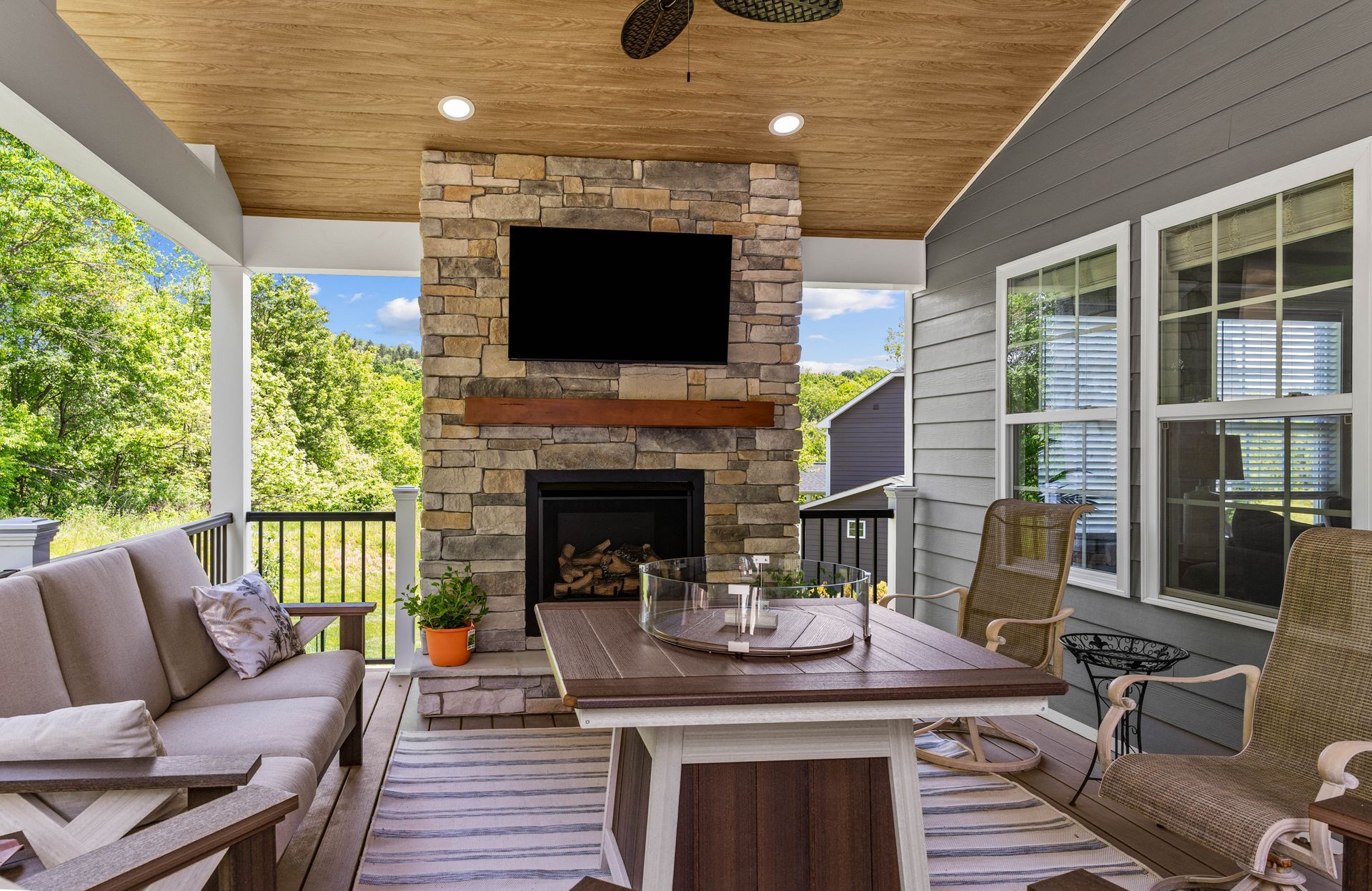 Covered patio with stone fireplace, sofa, chairs, and coffee table in a bright outdoor living space.