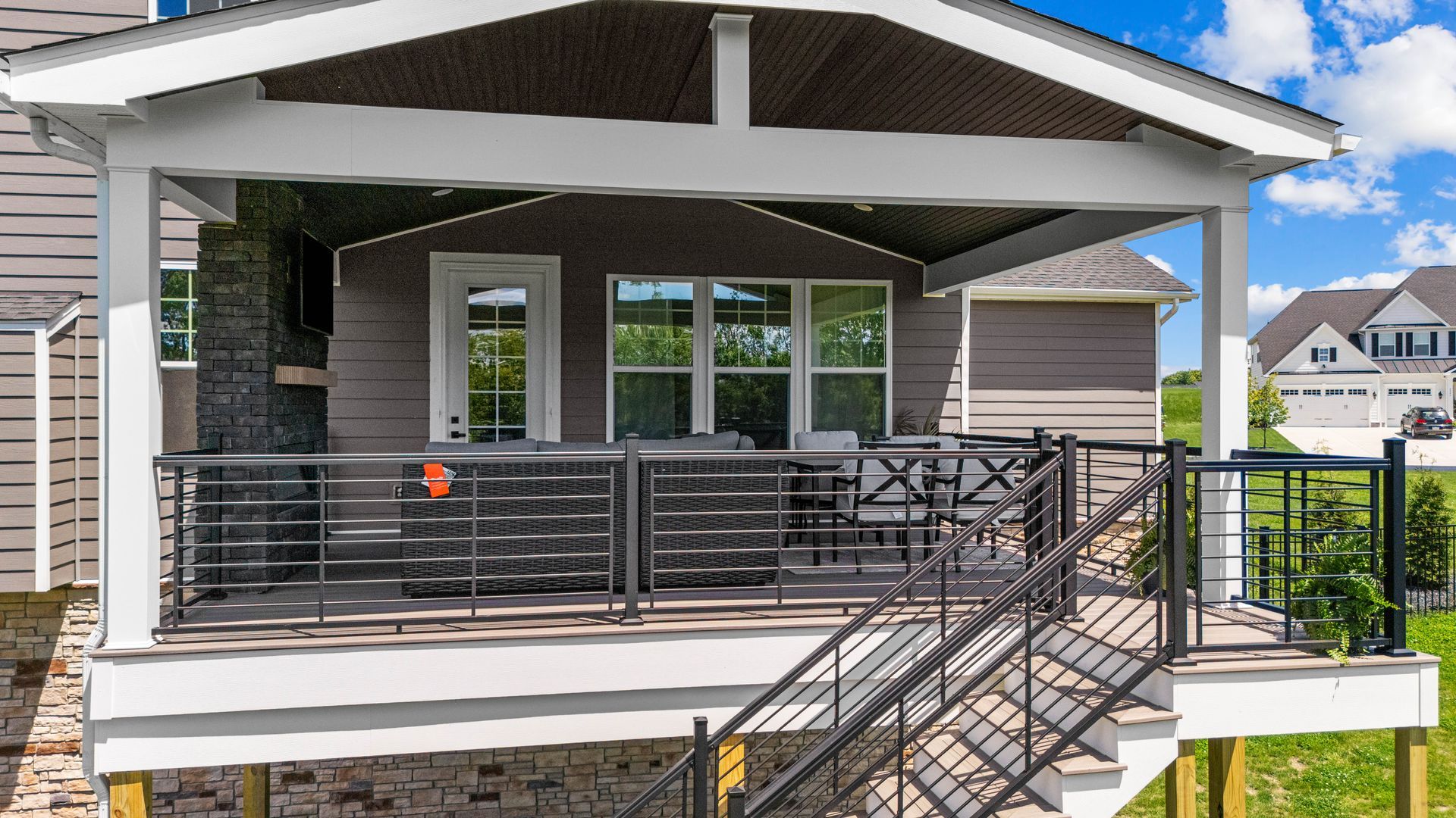 Modern house porch with metal railing, stairs, and covered patio
