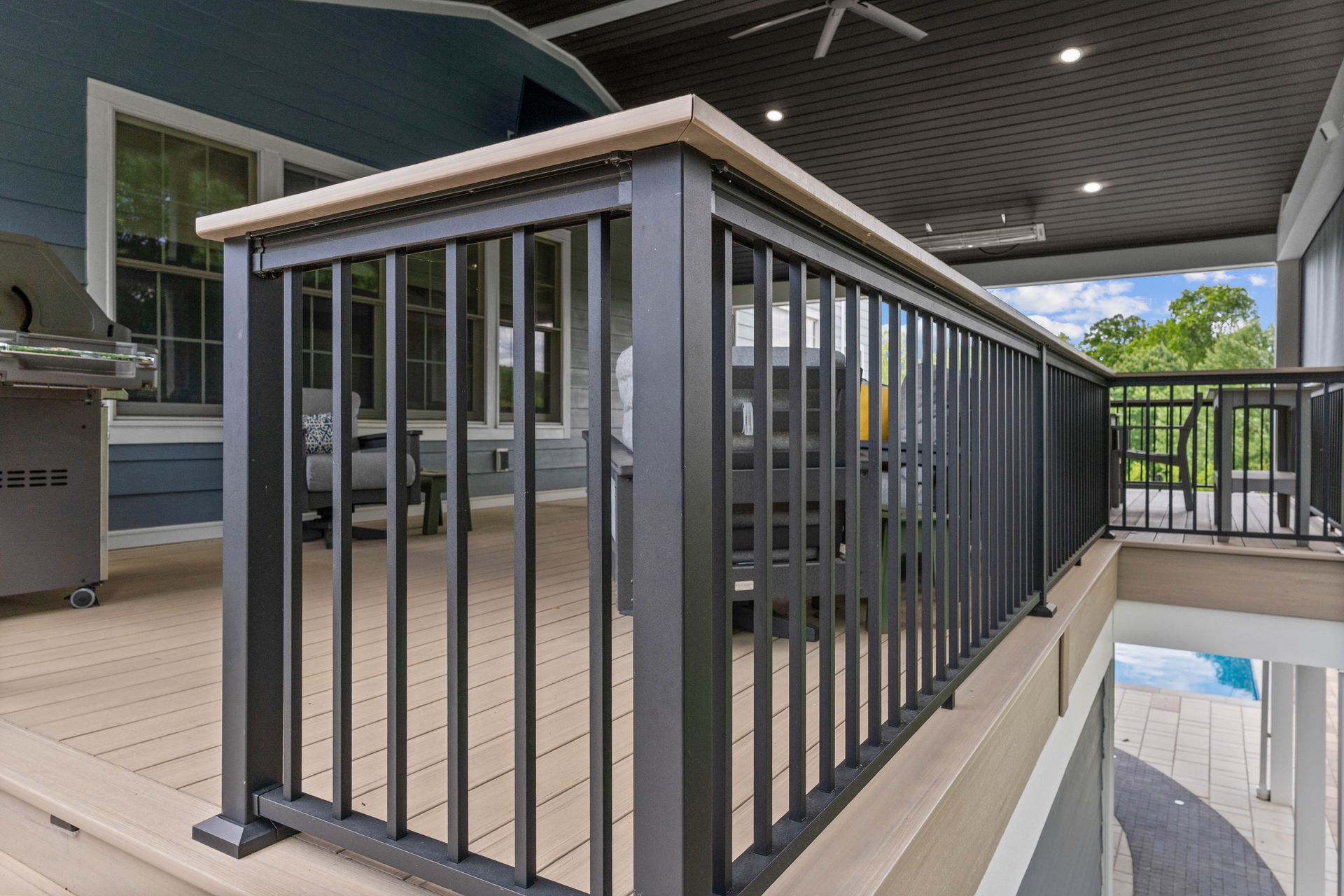 Indoor balcony with dark gray railings and concrete floor overlooking a pool area