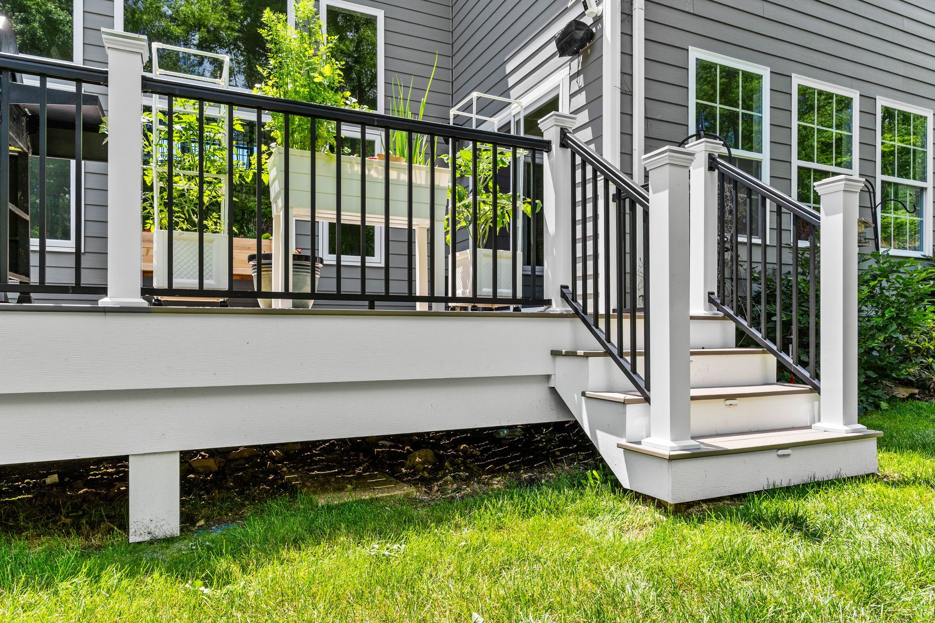 House porch with black railing, white steps, and a green lawn in front