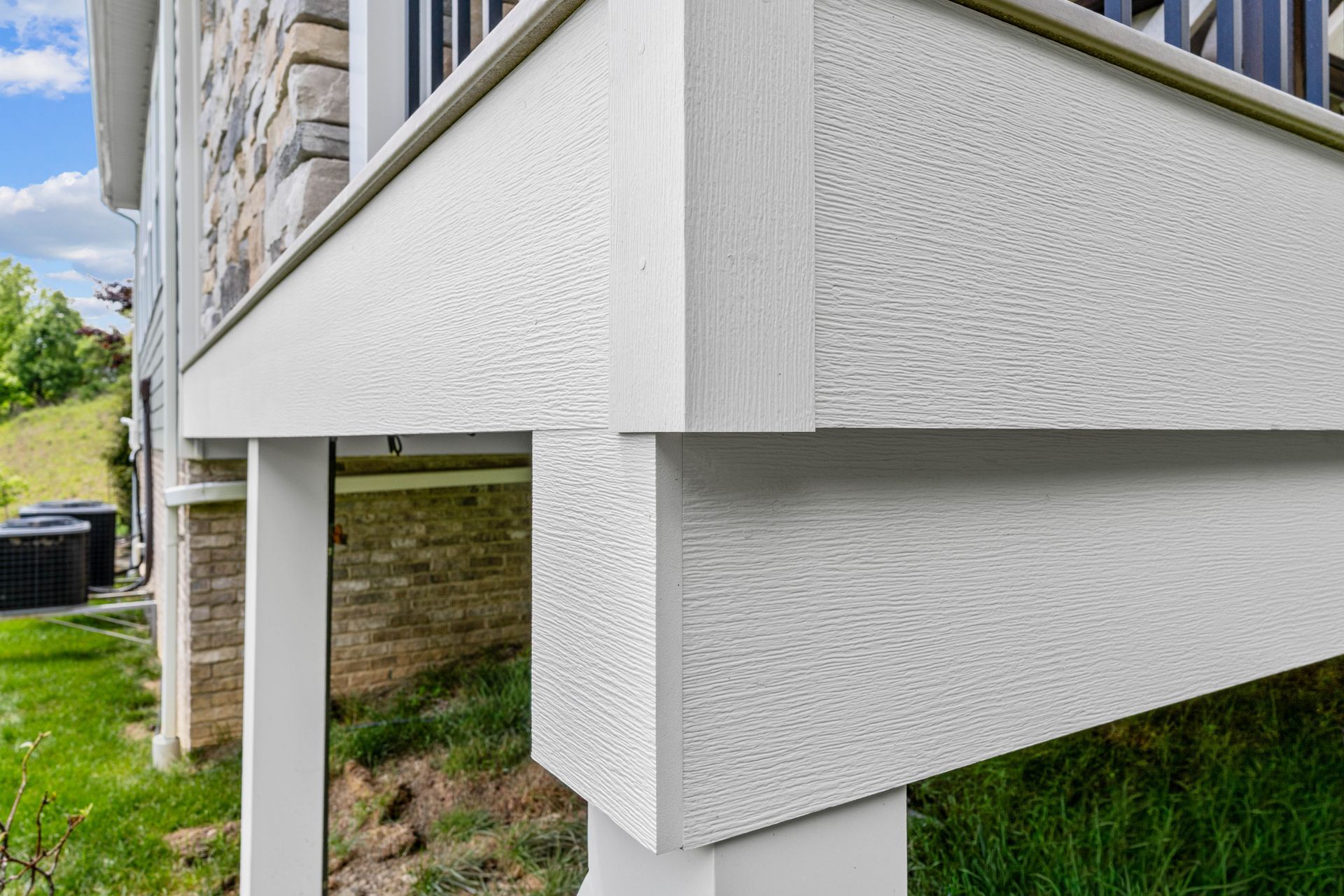 Raised house exterior with white siding and visible support posts over grassy ground