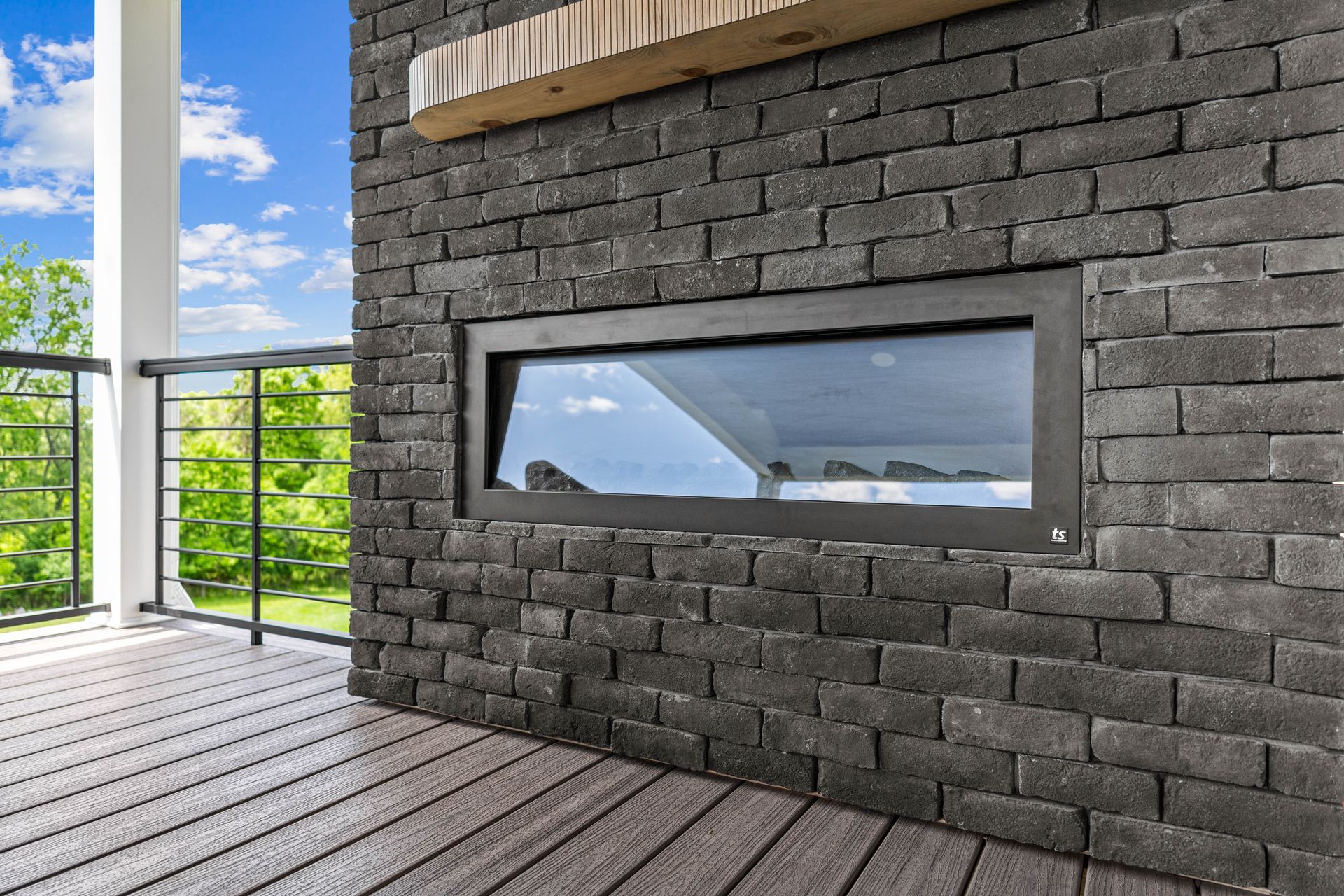 Modern brick wall with a long horizontal window overlooking a balcony and blue sky