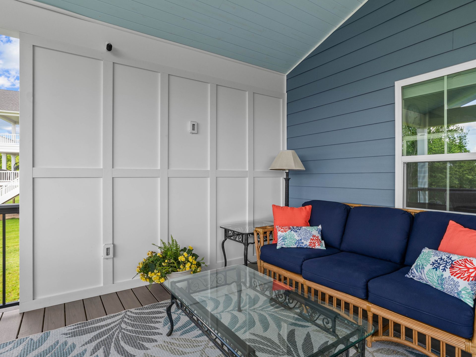 Covered patio with blue sofa, glass coffee table, and white storage doors