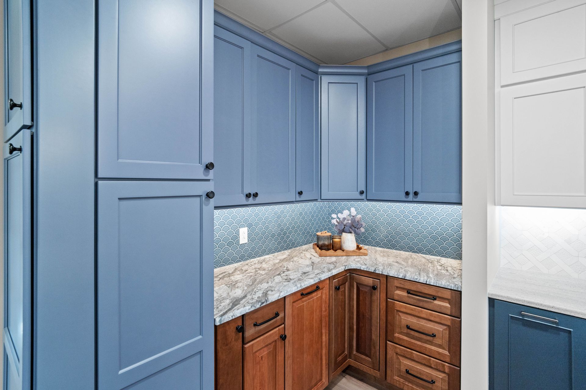 Blue and wood kitchen corner with tiled backsplash, granite countertop, and built-in cabinets