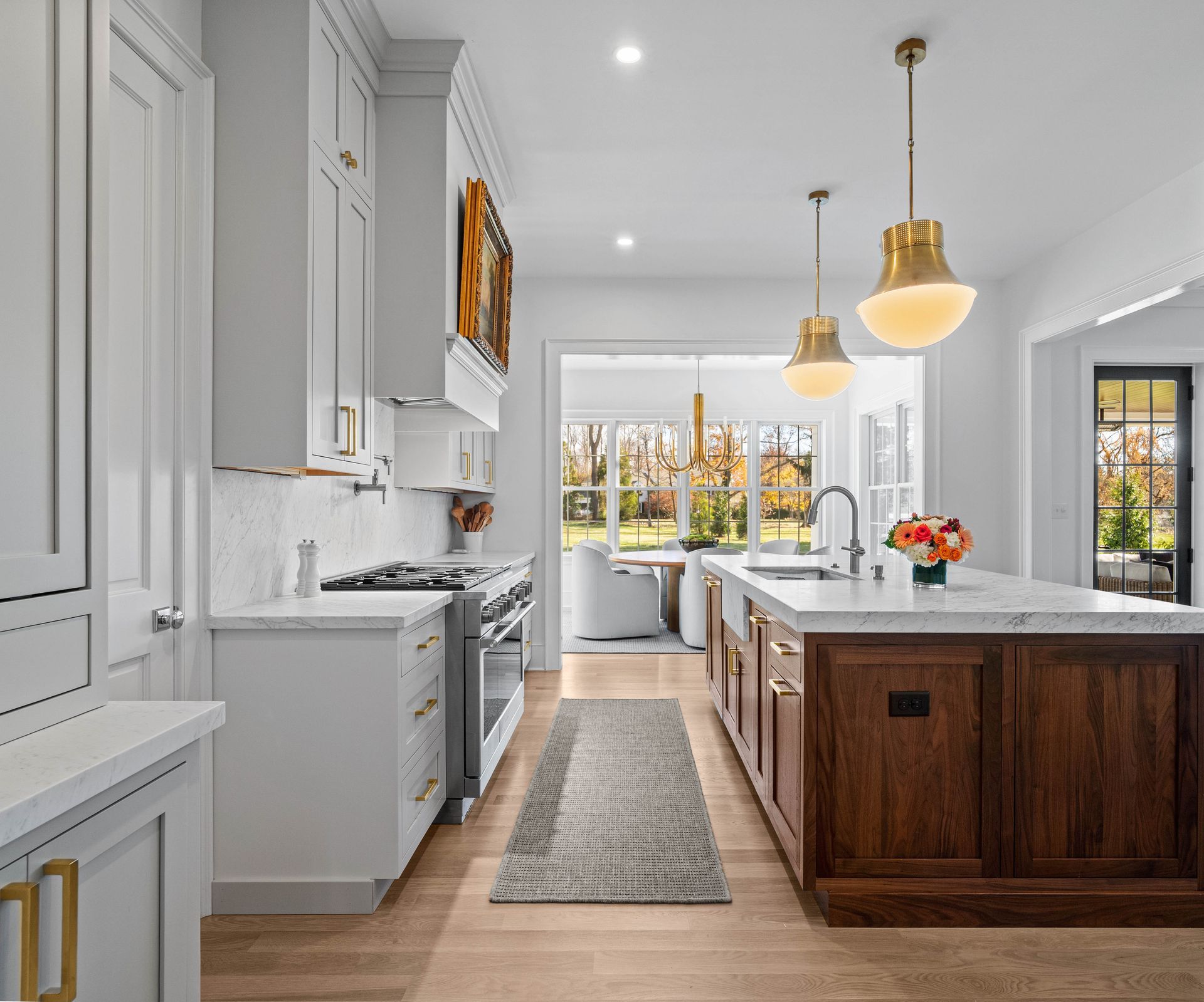 Bright modern kitchen with white cabinets, marble island, pendant lights, and a runner rug