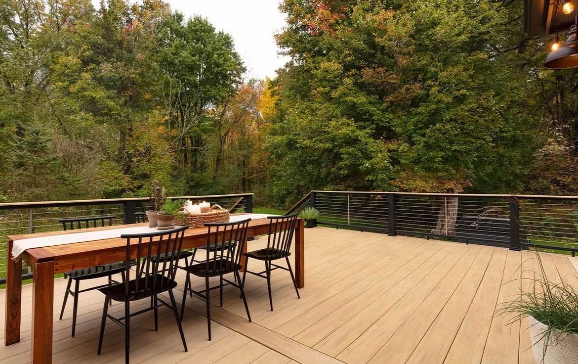 Outdoor deck with dining table and chairs, surrounded by trees.