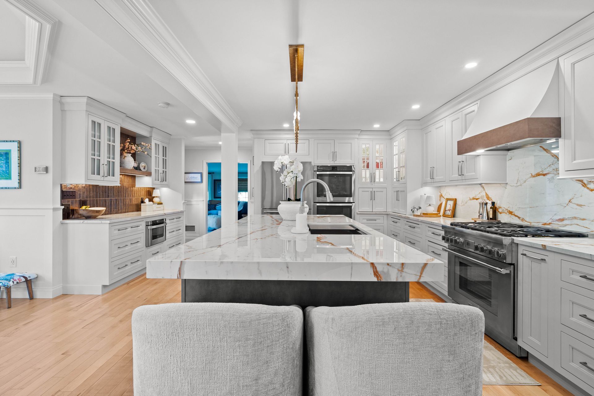 Bright modern kitchen with white cabinets, marble island, and gray bar stools