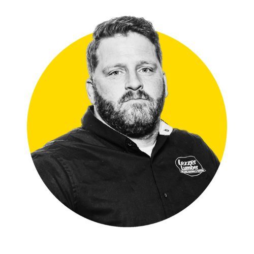 Man with beard, wearing black shirt with logo, inside a yellow circle.