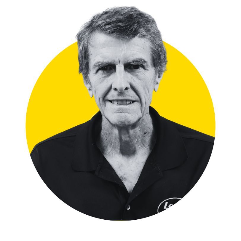 Man in black shirt with logo inside yellow circle; grayscale portrait.