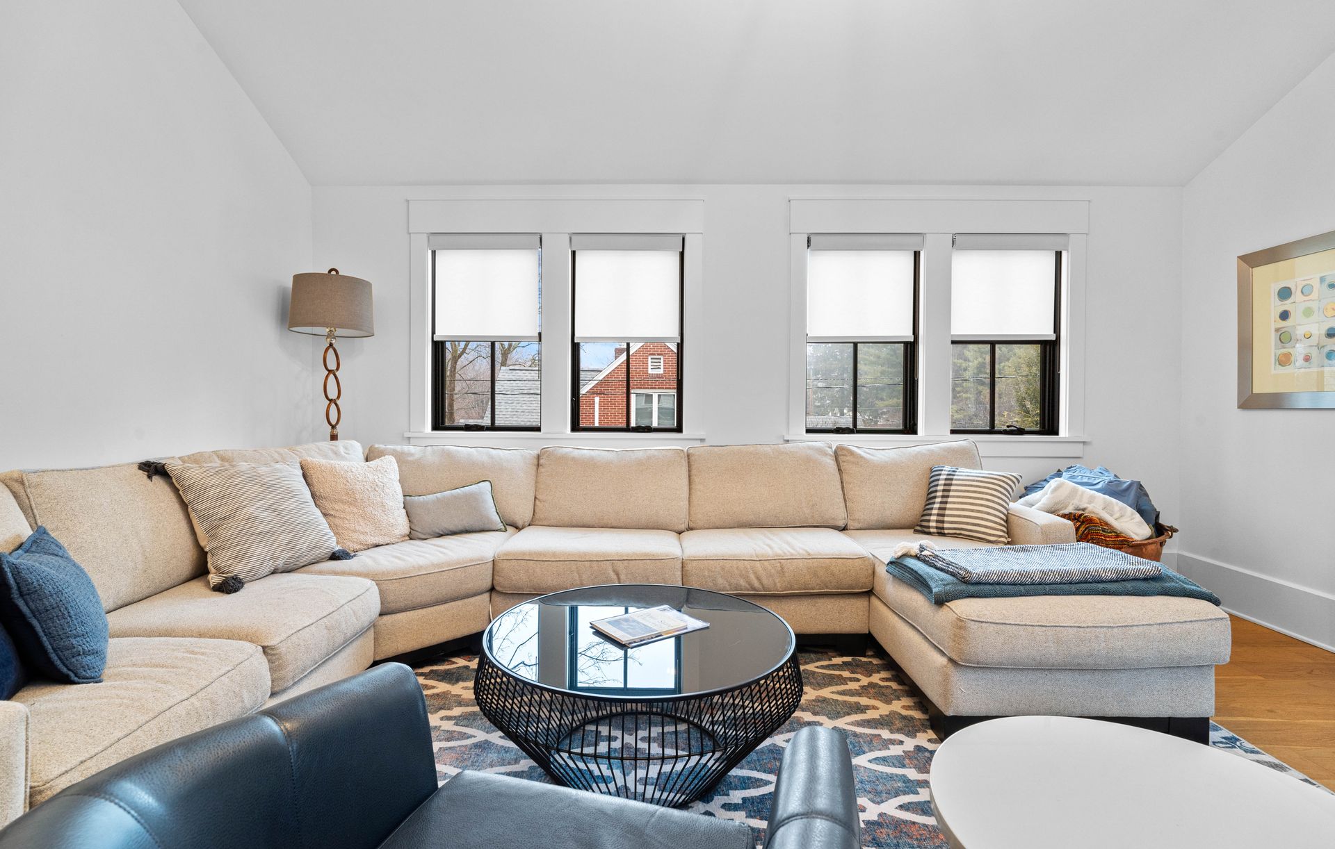 Bright living room with beige sectional sofa, round coffee table, windows, and patterned rug