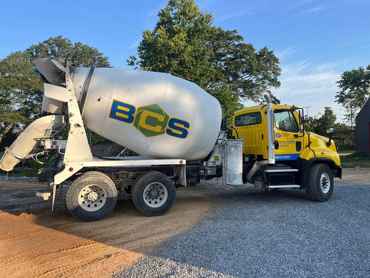 A bcs concrete mixer truck is parked in a gravel lot.