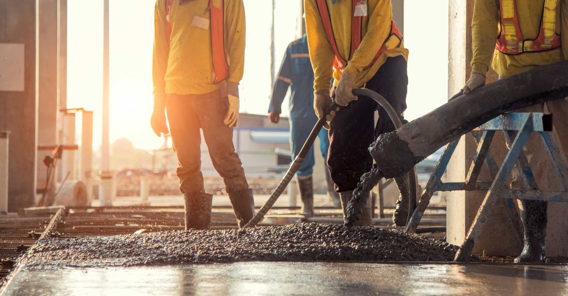 A group of construction workers are working on a concrete floor.