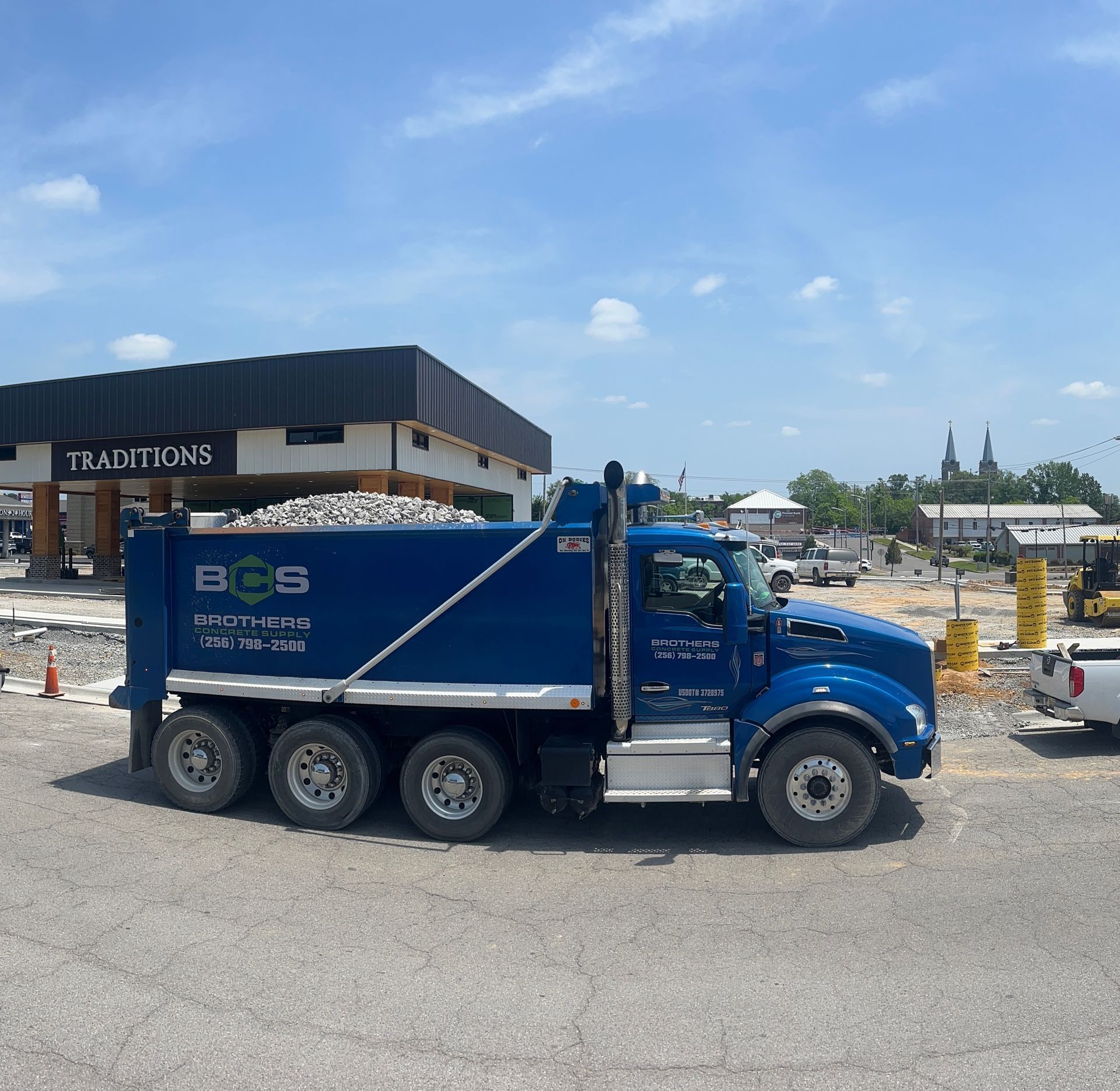 A blue dump truck is parked in front of a building that says traditions