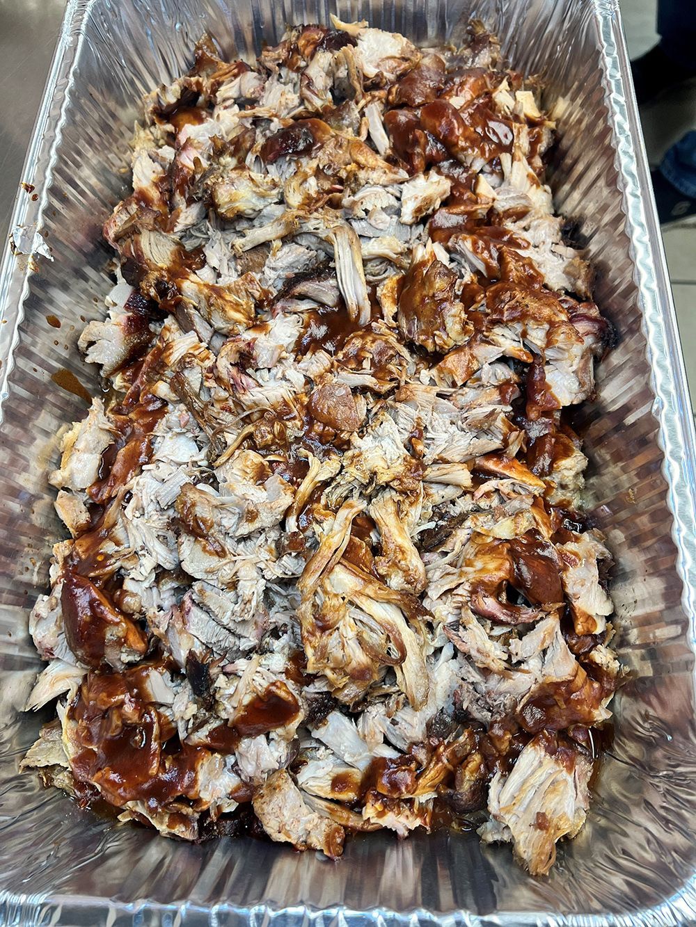 Aluminum foil tray filled with shredded pork and barbecue sauce.