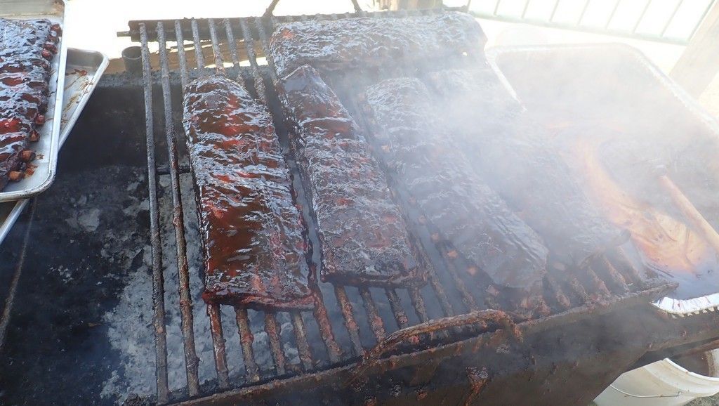 ribs are cooking on a grill with smoke coming out of it