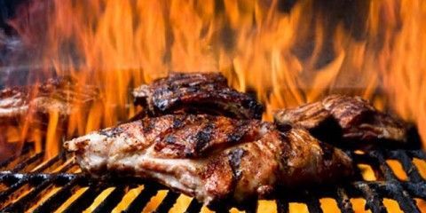 a piece of meat is cooking on a grill with flames behind it