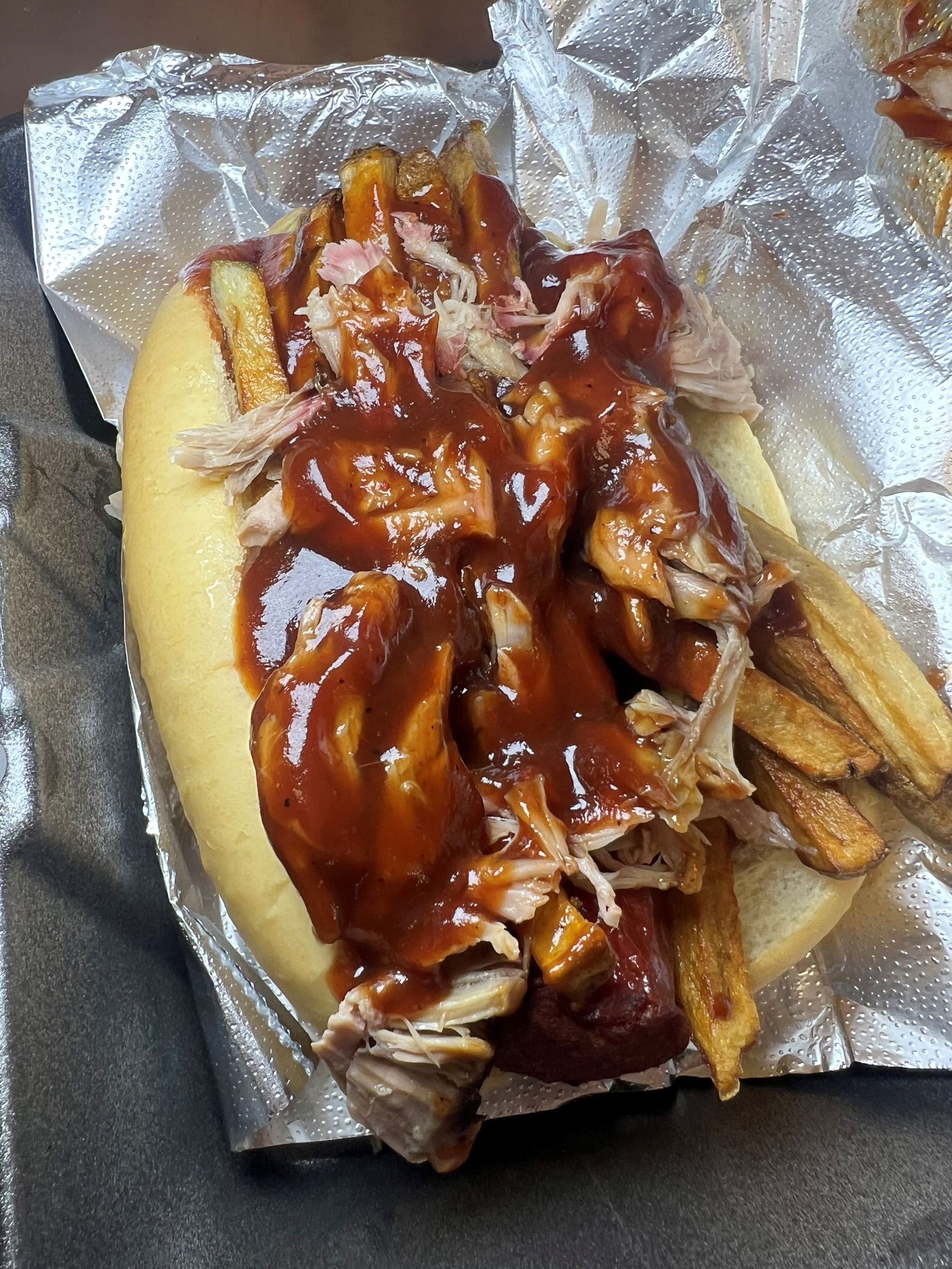 A pulled pork sandwich with french fries and barbecue sauce.