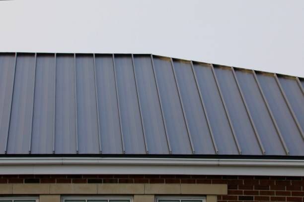 Gray metal roof over a brick building with white trim.