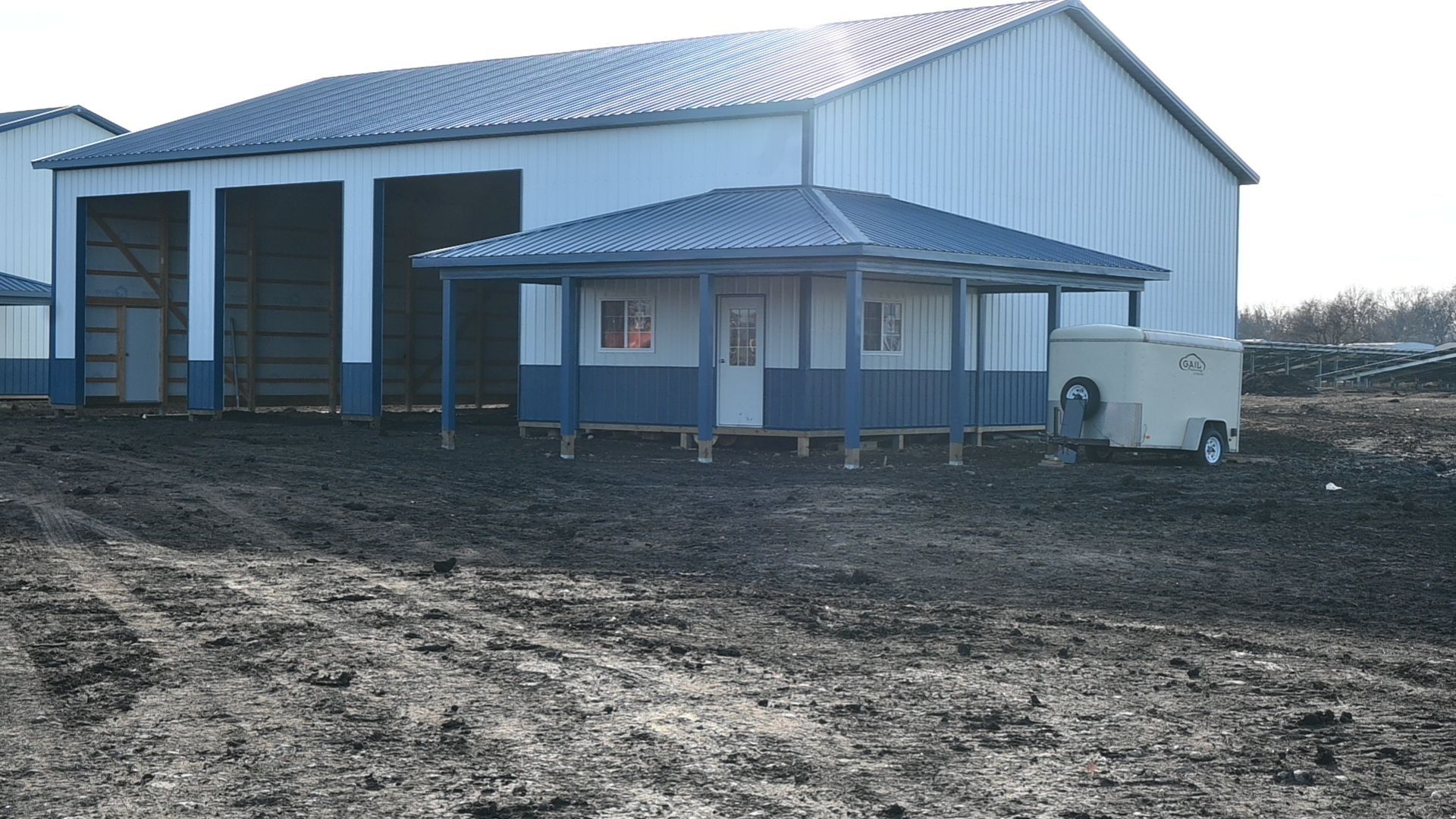 Large blue and white building with a small blue and white porch. Muddy foreground. Generator on the right.