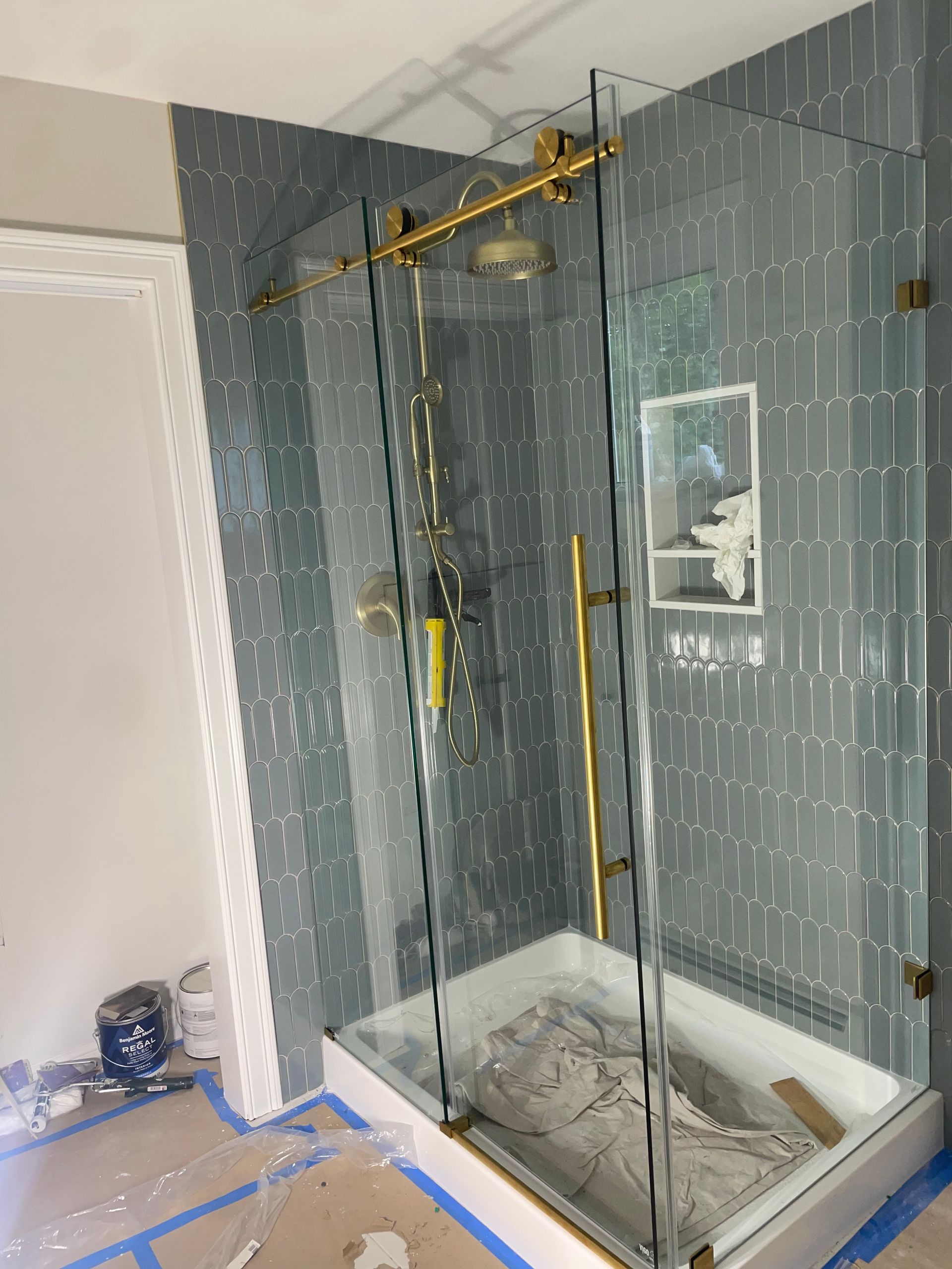 Newly installed shower with gold fixtures and gray tiled walls.