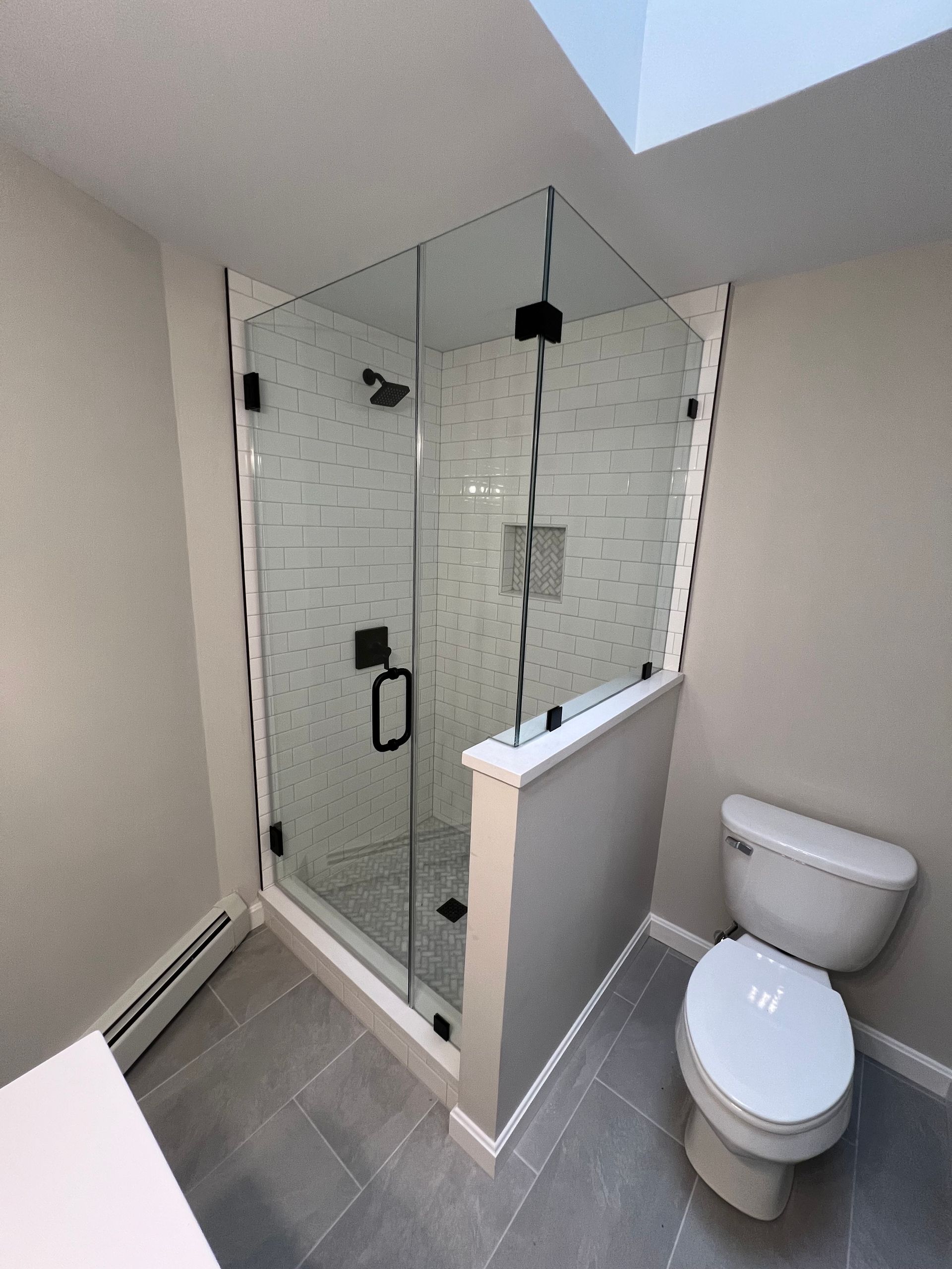 Modern bathroom with glass shower enclosure, white toilet, and gray tile floor.
