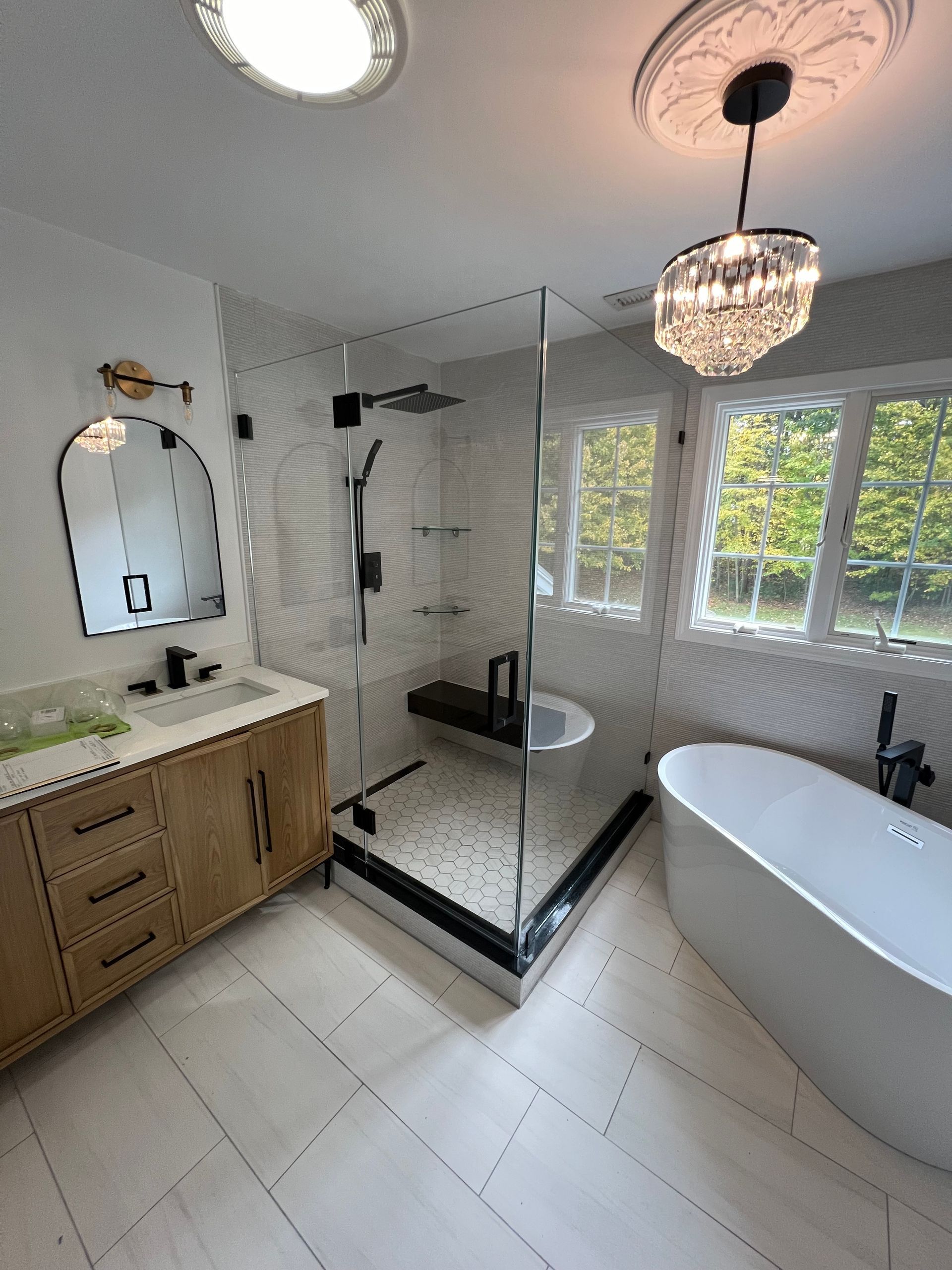 Modern bathroom with a glass shower, soaking tub, and vanity; white and light wood tones.