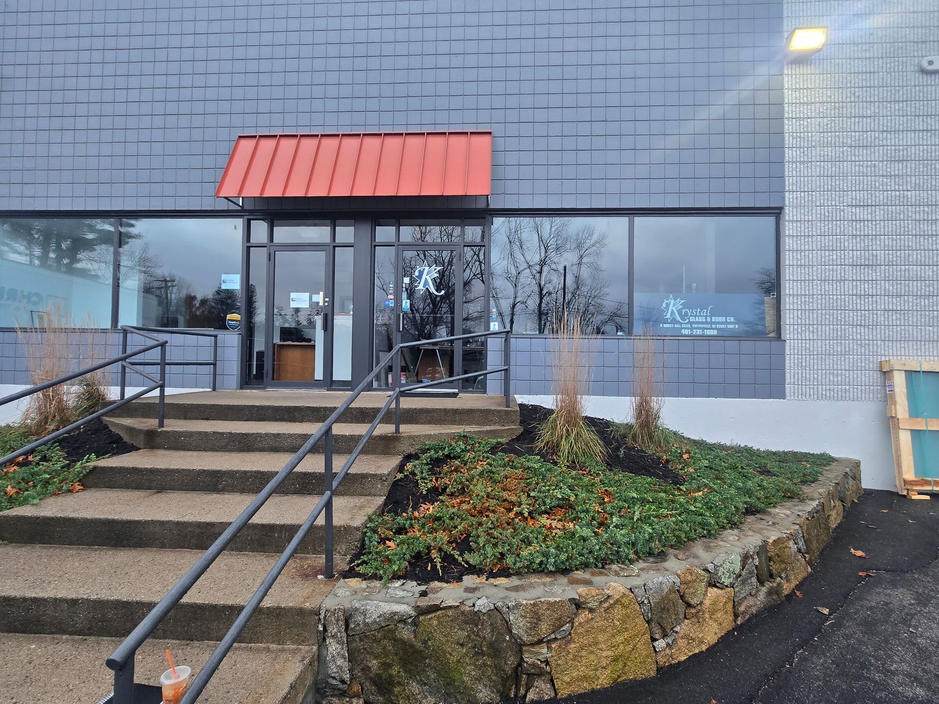Entrance to a building with a red awning over the door, steps, and handrails.