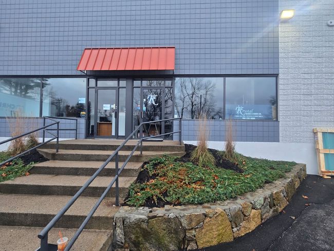 Entrance to a building with a red awning over the door, steps, and handrails.