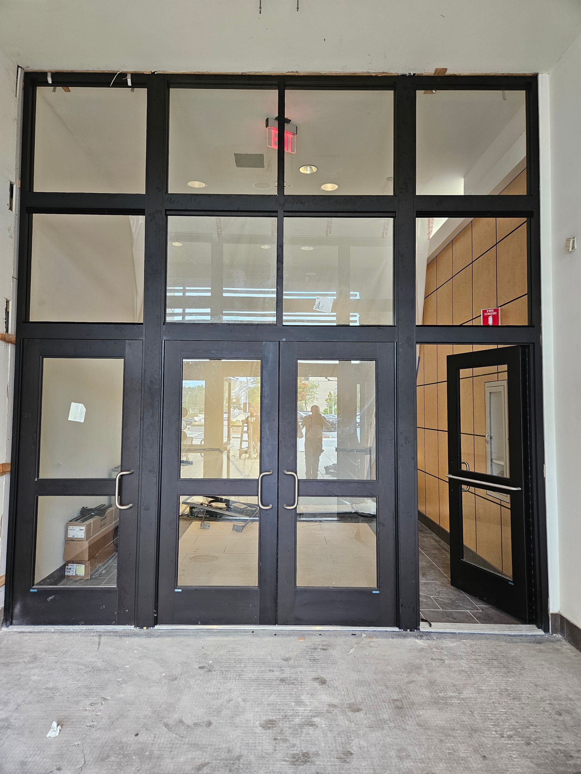 Black framed glass doors and windows, entryway with open side door.