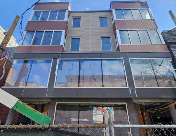Newly constructed multi-story building with large windows and brown and gray facade.