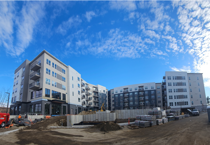 Apartment complex under construction, with multi-story buildings and a bright blue sky.