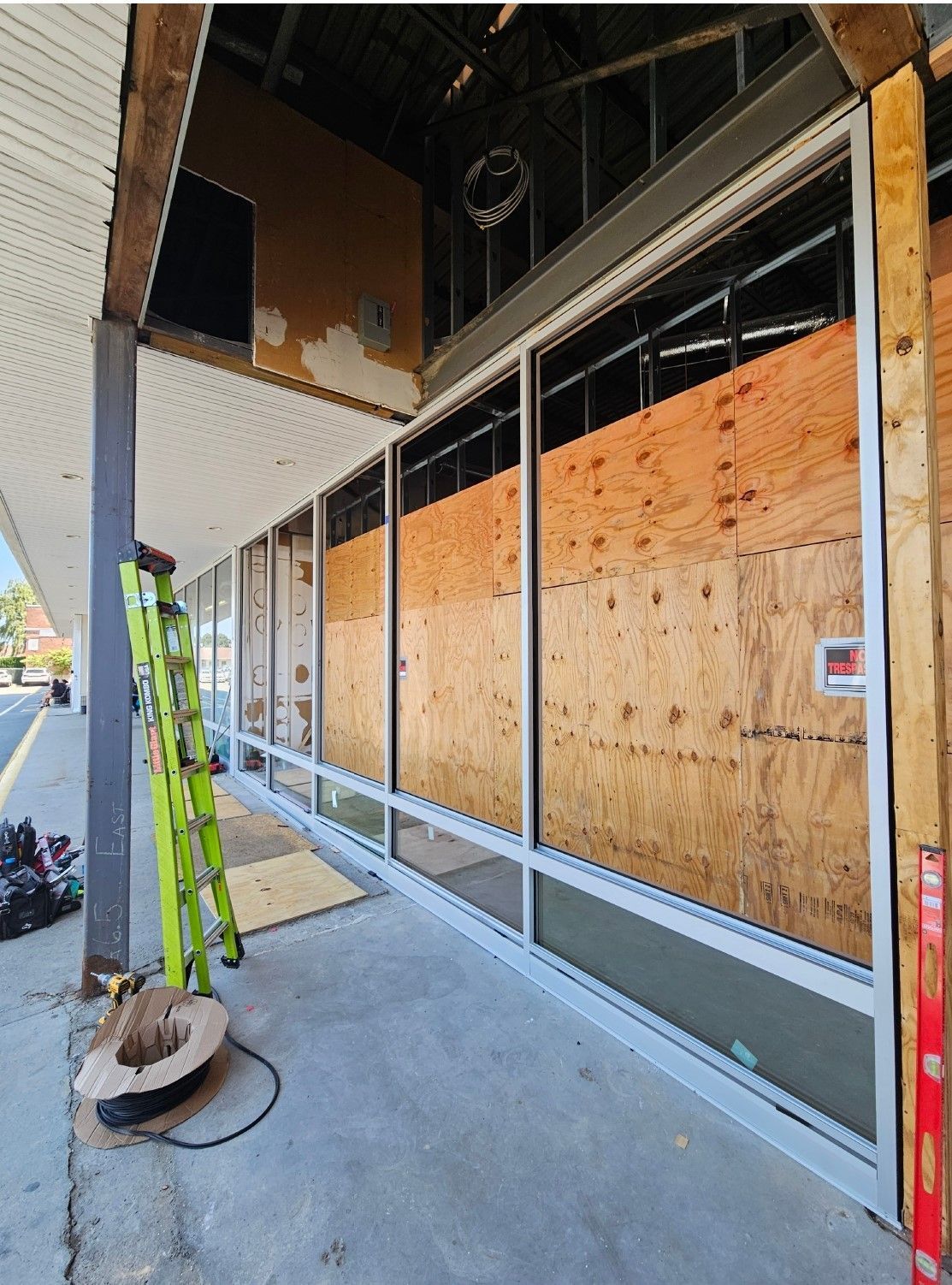 Building exterior under construction; boarded windows, metal framing, ladder, and tools.