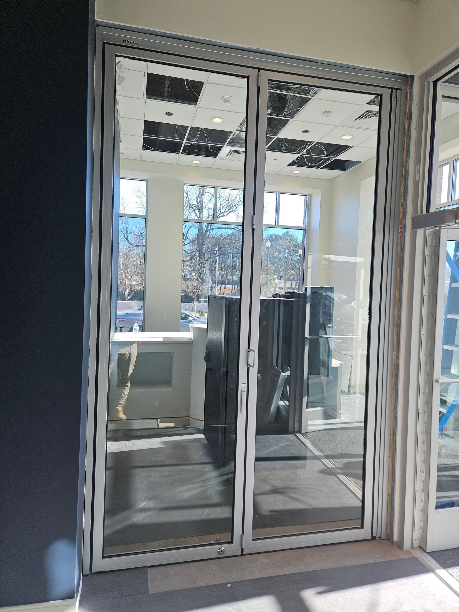 Glass double doors with white frames leading into a room with windows and display cases.