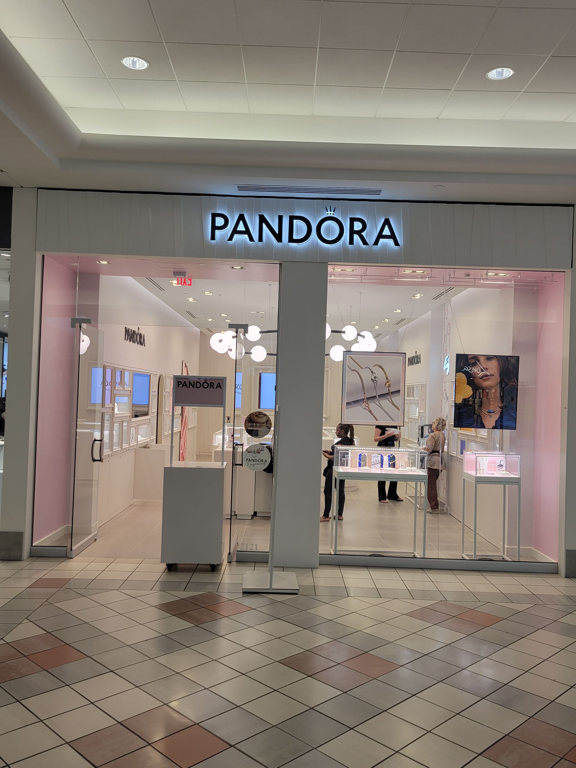 Pandora store front in a mall, lit with white, featuring glass doors and displays.