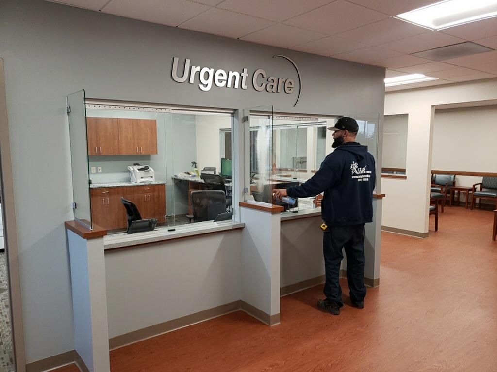 A person at the Urgent Care desk. A gray and white interior. The person is interacting with the staff.