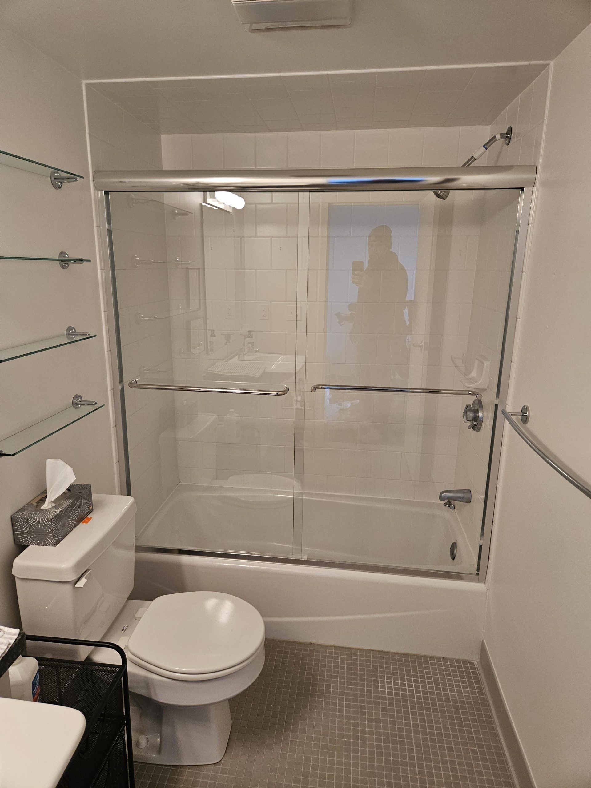 Bathroom with a shower, toilet, and shelves on the wall.
