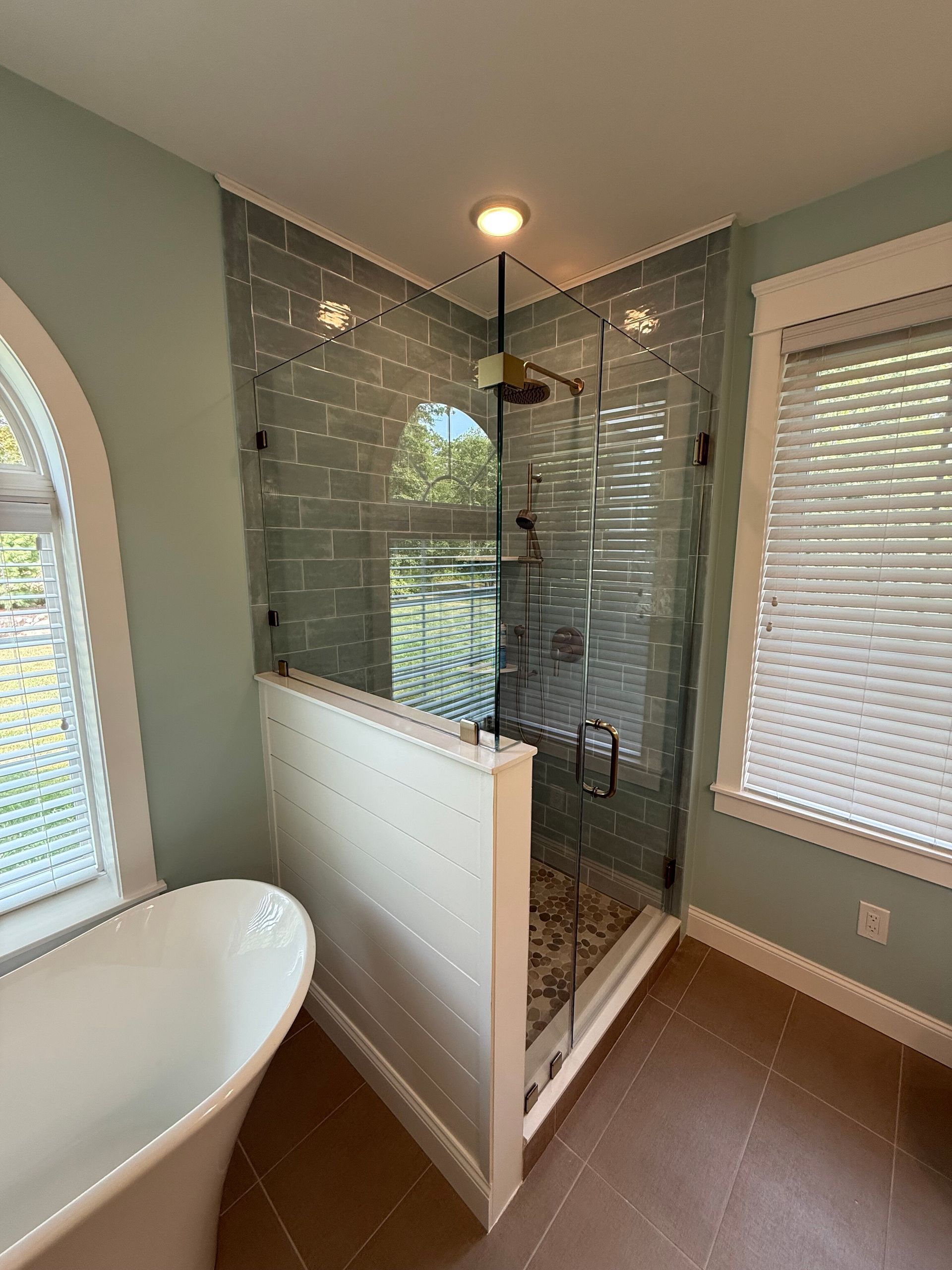 A bathroom with a glass shower enclosure and a freestanding bathtub.